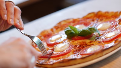 person about to slice pizza on white plate tasteful zoom background