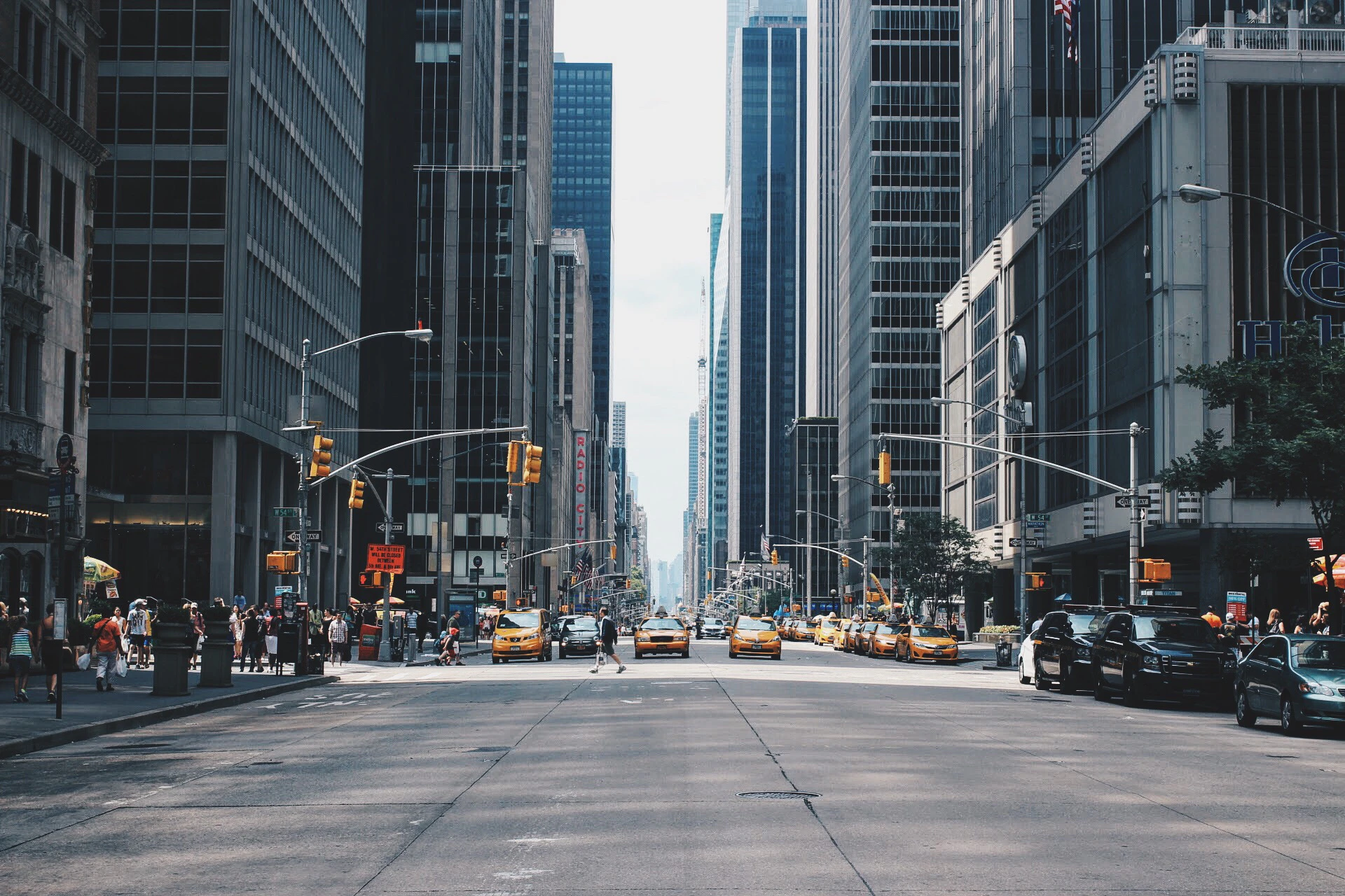 Busy New York street with yellow taxis and mid-rise buildings.
