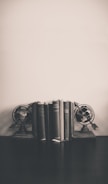 A vintage globe and antique books stacked on a dark wood shelf.