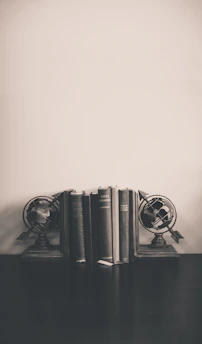 A vintage globe and an old leather-bound history book on a wooden desk.