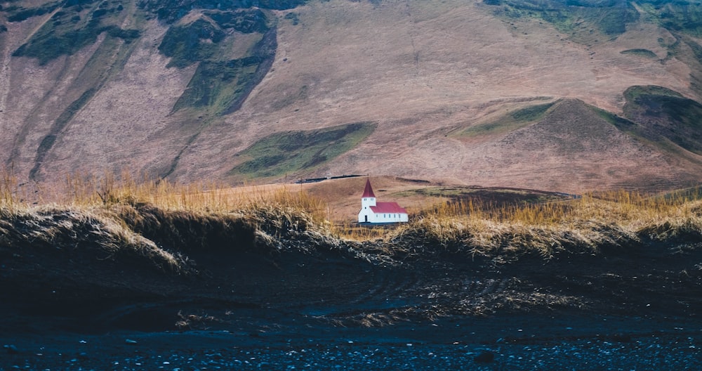 white red and chapel on grass field near mountain