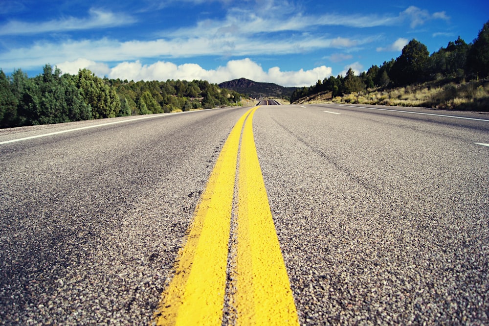 gray concrete road with no vehicle under blue and white skies