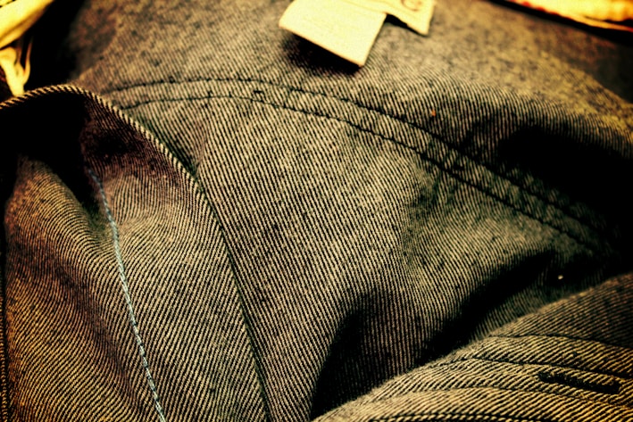Close-up of premium denim jeans fabric with detailed stitching.