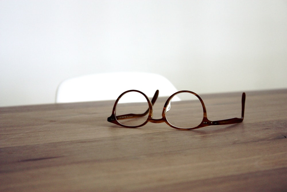 eyeglasses with brown frames on brown wooden surface