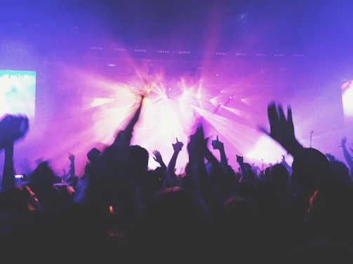 Close-up of hands in the air, illuminated by neon lights, capturing the energy of the crowd.