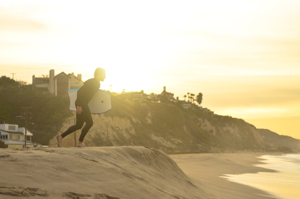 hombre que lleva bodyboard blanco en playa de arena gris