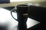 White mug featuring a custom golden logo on a minimalist background.