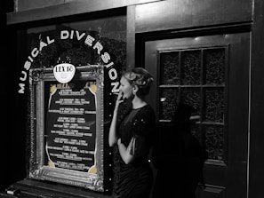 A woman in vintage attire and styled hair stands outside a venue with a decoration sign that reads 'Musical Diversion'. The marquee lists various jazz performances and dates. The scene combines elements of retro fashion with a music theme.