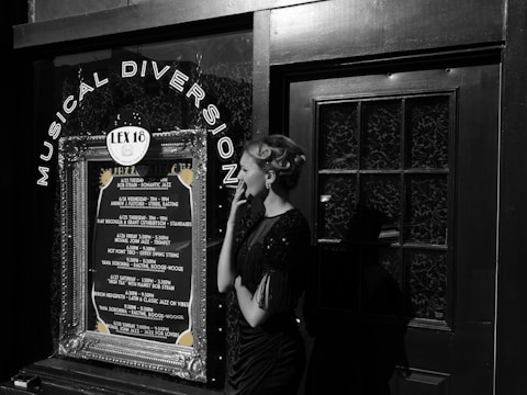 A woman in vintage attire and styled hair stands outside a venue with a decoration sign that reads 'Musical Diversion'. The marquee lists various jazz performances and dates. The scene combines elements of retro fashion with a music theme.