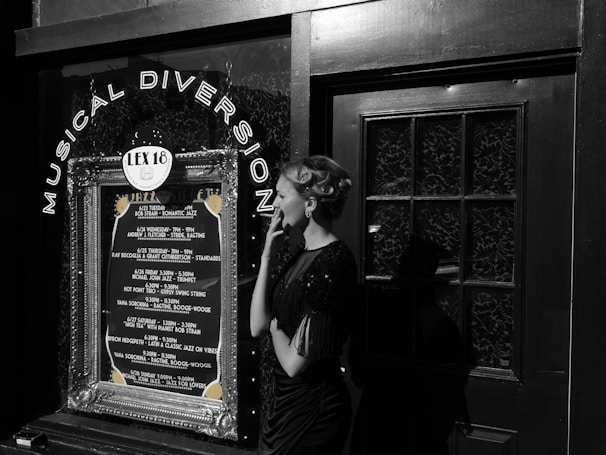 A woman in vintage attire and styled hair stands outside a venue with a decoration sign that reads 'Musical Diversion'. The marquee lists various jazz performances and dates. The scene combines elements of retro fashion with a music theme.
