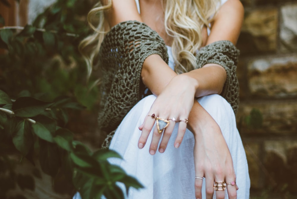 woman sitting beside plant and concrete wall