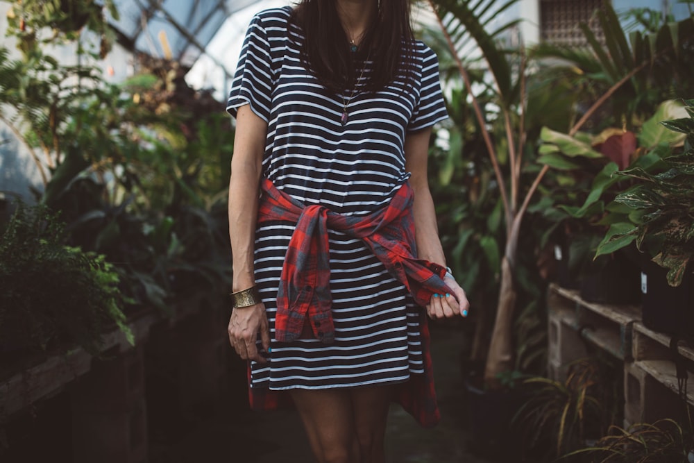 woman wearing black and white striped dress standing in isle near green plants