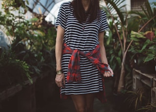 woman wearing black and white striped dress standing in isle near green plants