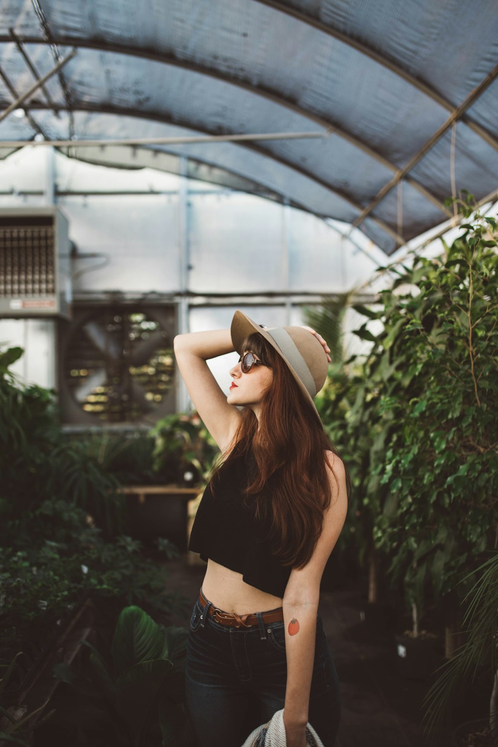 shallow focus photography of woman posing while holding her hat at the garden