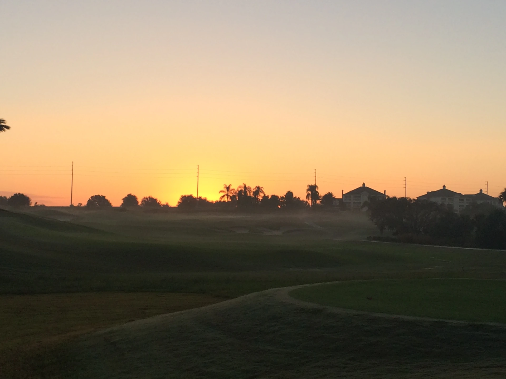 A serene sunset over a coastal golf course, casting golden hues on the rolling greens of Murcia.