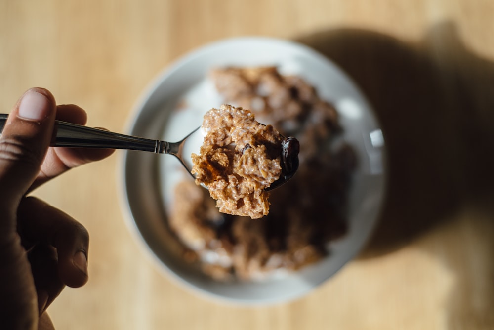 Person, die Teaspon mit Müsli hält