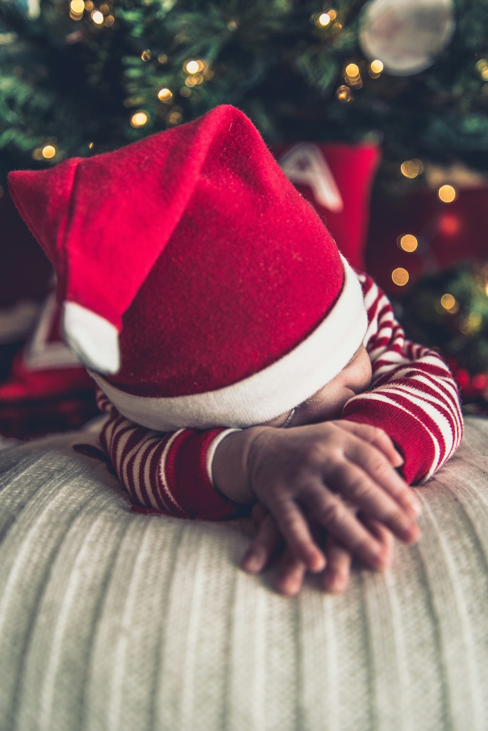 A baby wearing a Christmas outfit and Santa hat.