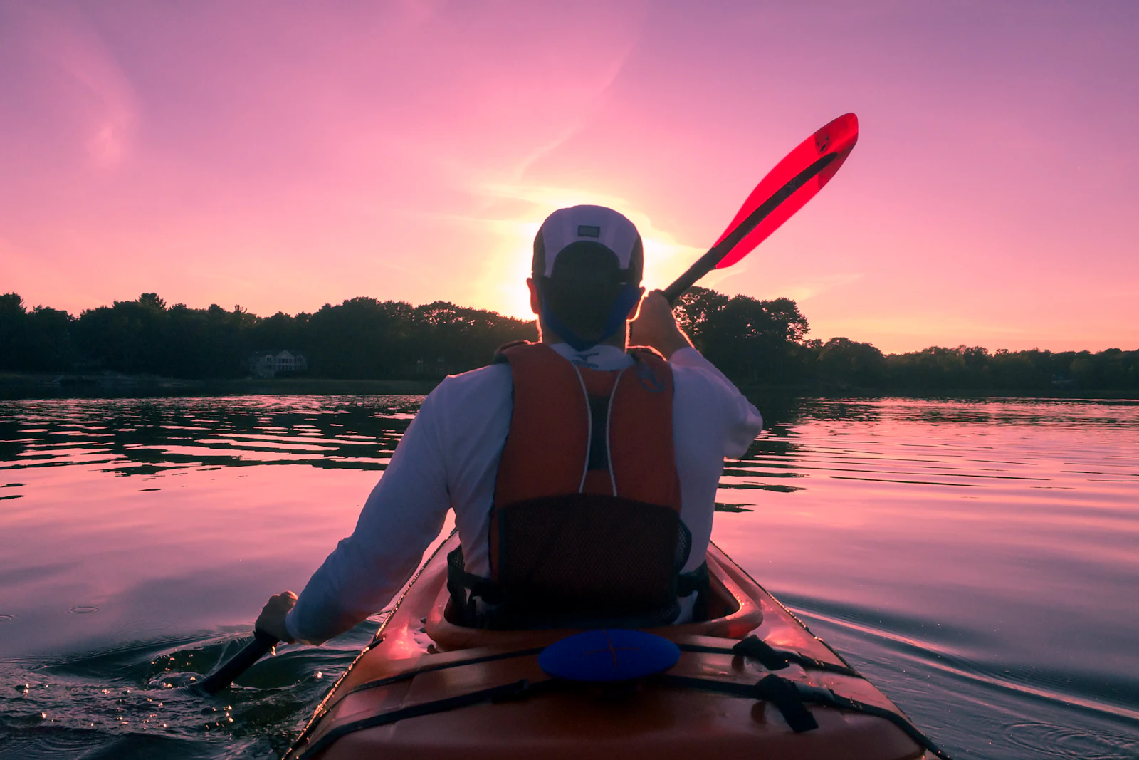 Persona remando en kayak en aguas abiertas con equipo preparado para una excursión de un día