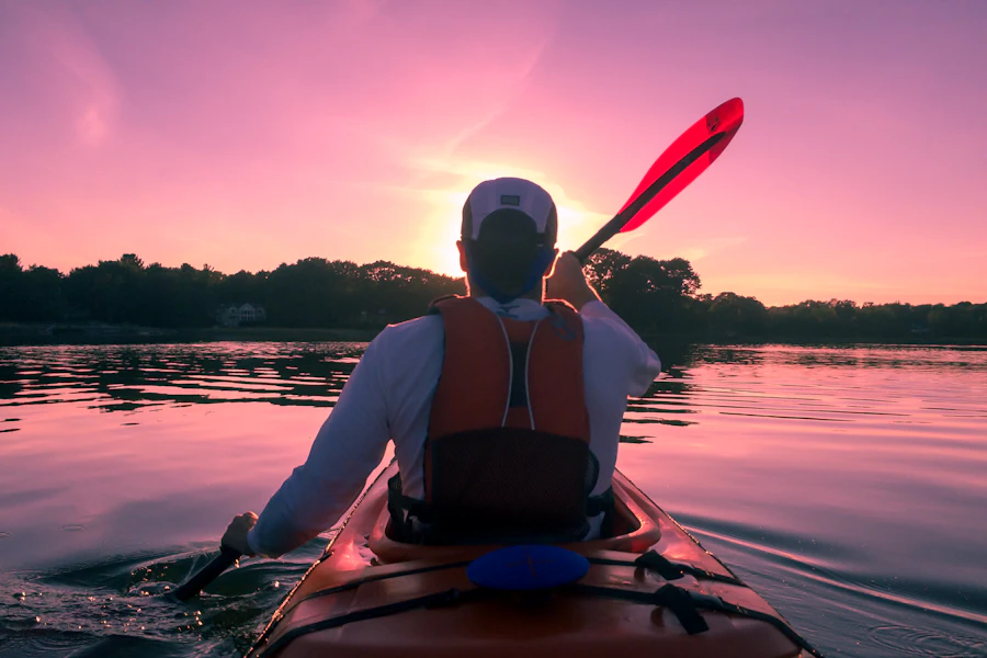 Person paddling a kayak on open water with gear packed for a day trip