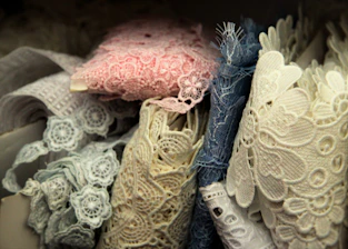 Soft lavender-hued fabric swatches layered with delicate lace and hand-drawn pattern sketches.