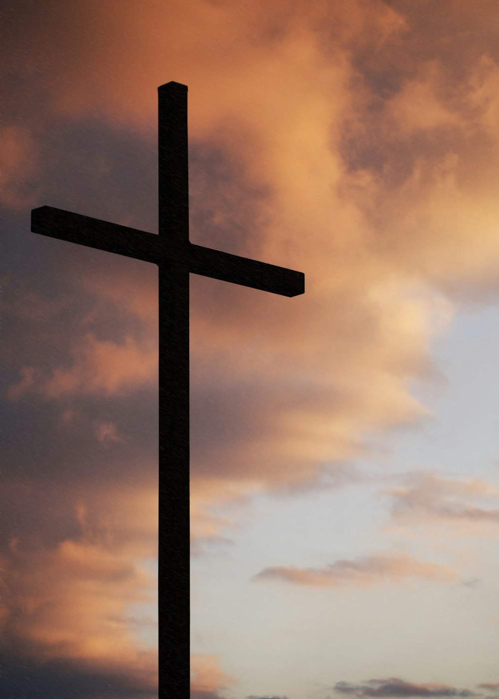 silueta de una cruz grande bajo el cielo naranja