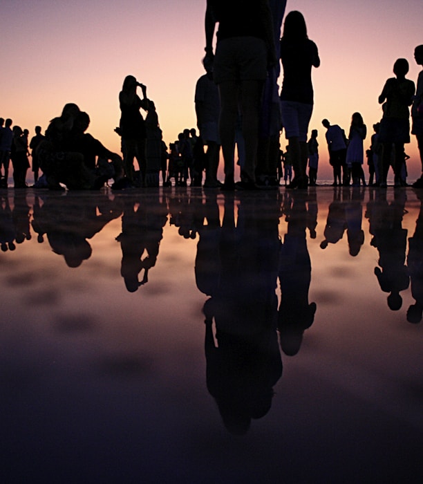 silhouette of people standing on mirror during golden hour