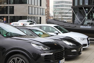 A fleet of rental cars parked outside a sleek urban office building.