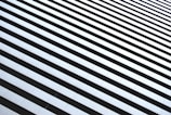 A series of parallel black and white horizontal lines create an optical illusion of depth and perspective. The lines are evenly spaced, with a clear contrast between the dark and light areas.