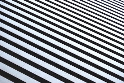 A series of parallel black and white horizontal lines create an optical illusion of depth and perspective. The lines are evenly spaced, with a clear contrast between the dark and light areas.