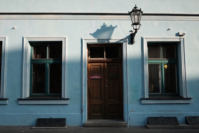 A freshly painted living room wall in soft pastel blue with sunlight streaming through the window.
