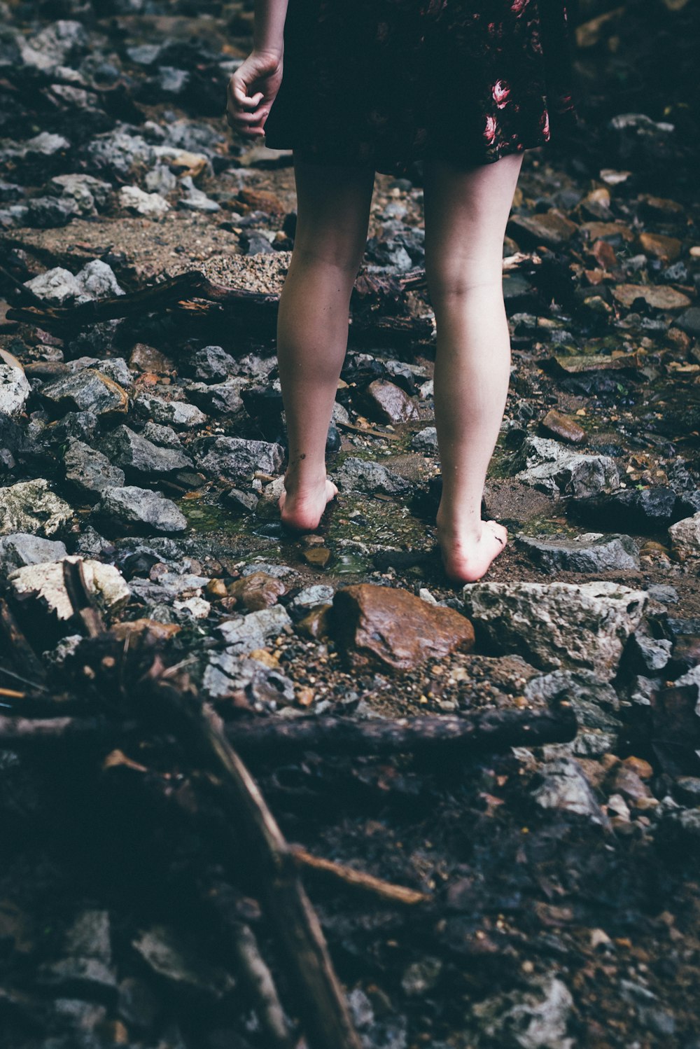 mulher em pé em rochas com água fluindo