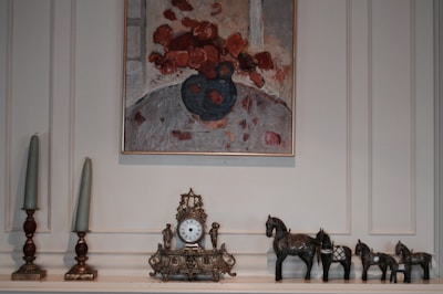 An elegantly arranged mantelpiece adorned with candles, greenery, and a vintage clock.