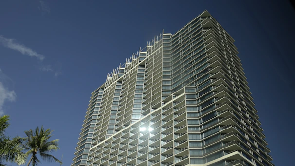Modern apartment building with balconies and palm trees under a clear blue sky in Florida.