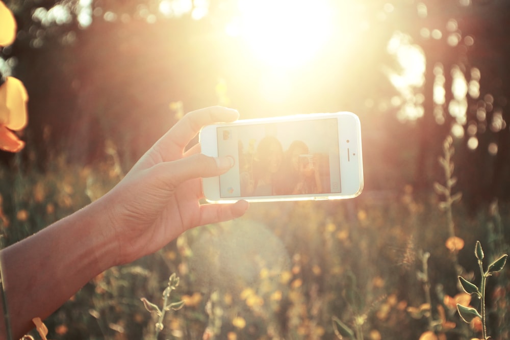 personne tenant un smartphone blanc