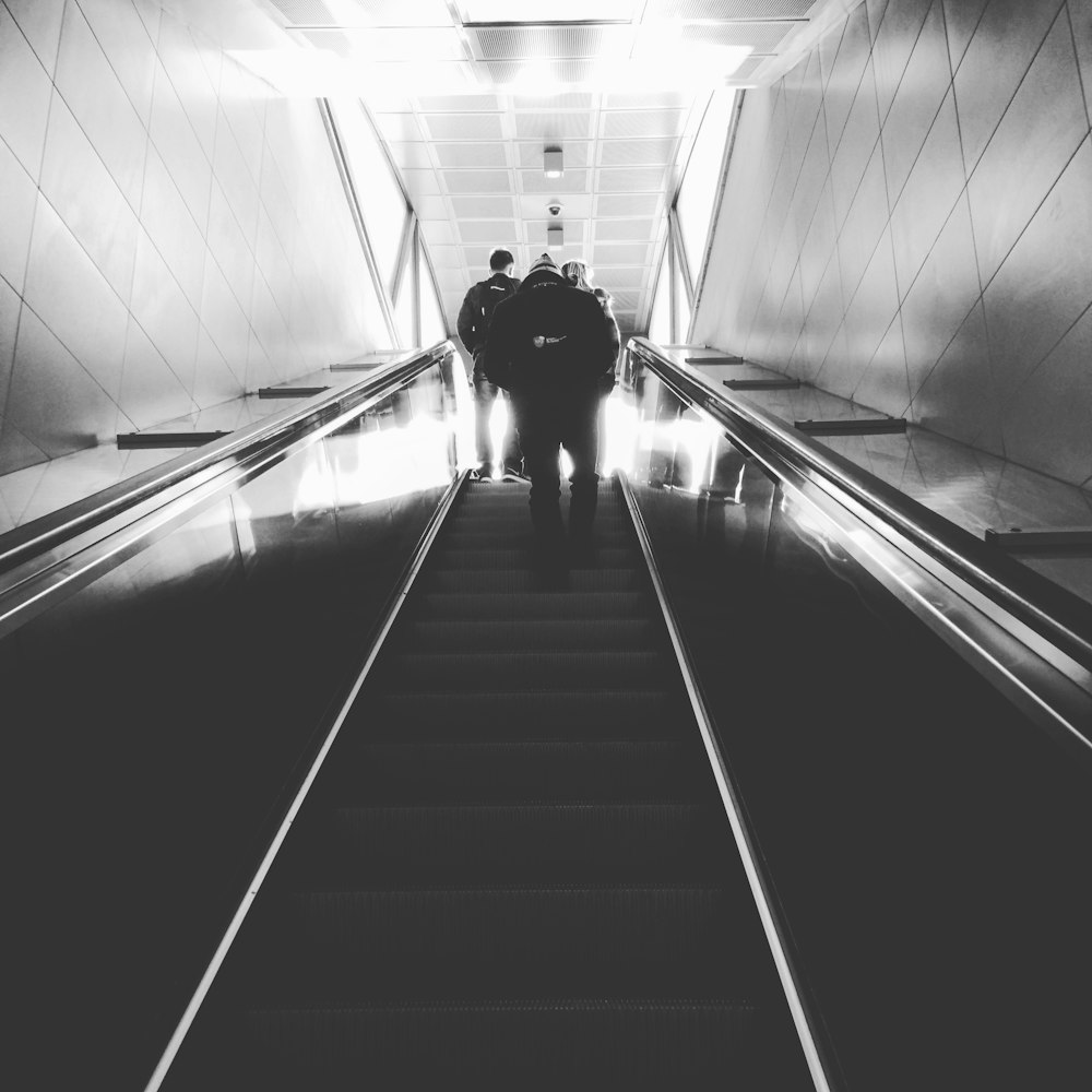 grayscale photography of man on escalator