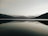 A serene lake reflecting the sky, with mountains in the background.