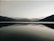 A serene lake reflecting the sky, with mountains in the background.