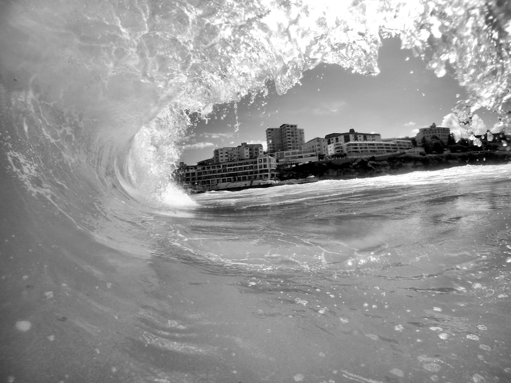 A gray image taken inside of a wave as it splashes overhead.