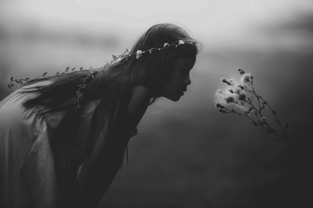 grayscale photo of girl looking at flowers