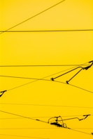 Cables crisscrossing against a bright yellow background with a few mechanical components attached.