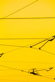 Cables crisscrossing against a bright yellow background with a few mechanical components attached.