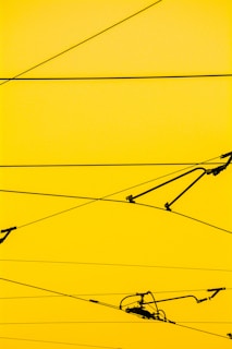 Cables crisscrossing against a bright yellow background with a few mechanical components attached.