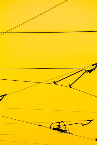 Cables crisscrossing against a bright yellow background with a few mechanical components attached.