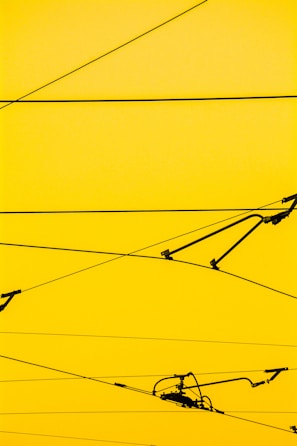 Cables crisscrossing against a bright yellow background with a few mechanical components attached.
