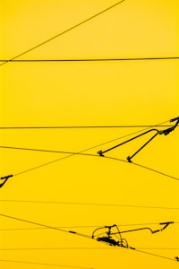 Cables crisscrossing against a bright yellow background with a few mechanical components attached.