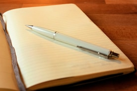 An open journal with a pen resting on a wooden table.