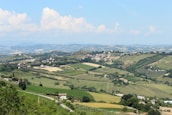 A picturesque landscape of rolling hills and charming villages under a bright blue sky.