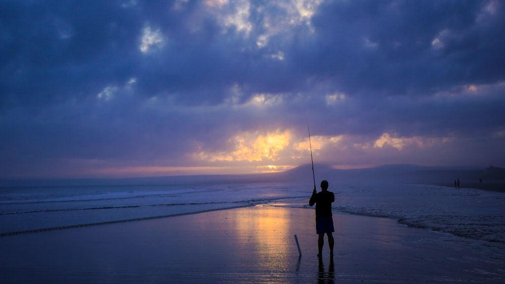 silhouette of person fishing on body of water