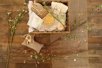 A cozy flat lay of natural bath salts, a wooden spoon, and a soft towel on a rustic wooden surface.