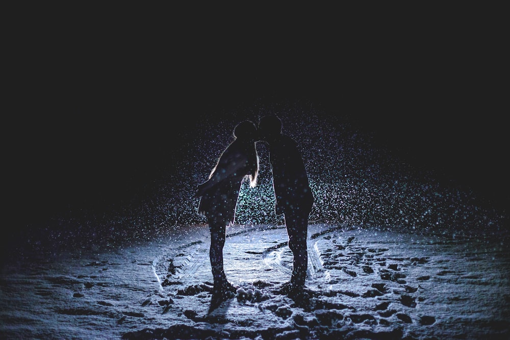 man and woman kissing in the middle of the rain